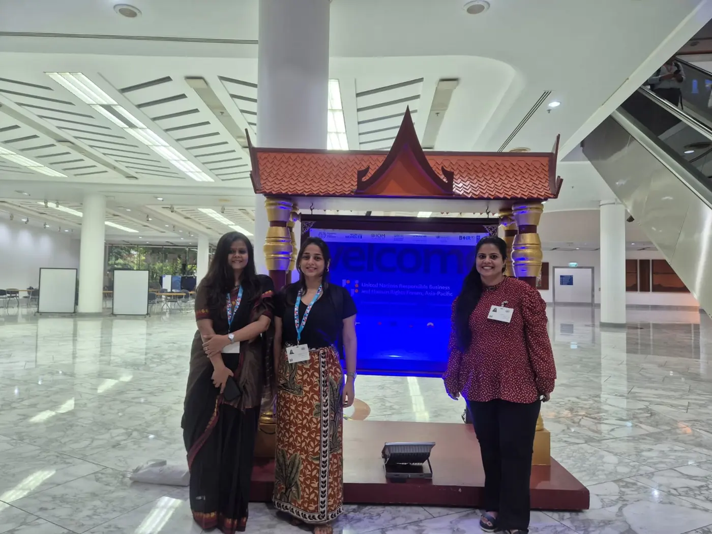 Three delegates at the welcome sign of the UN Responsible Business and Human Rights Forum, Asia-Pacific 2026
